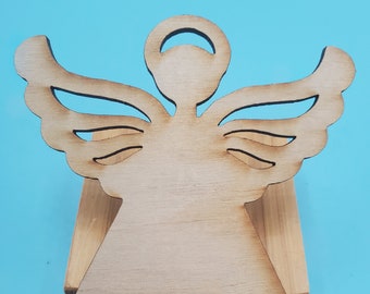 May include: A wooden angel figurine with outstretched wings and a halo. The angel is light brown and stands on a rectangular wooden base. The background is a solid light blue.
