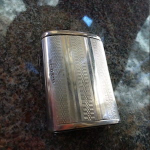 May include: A silver rectangular box with an engraved design and the text "WARD & CO" on the side.