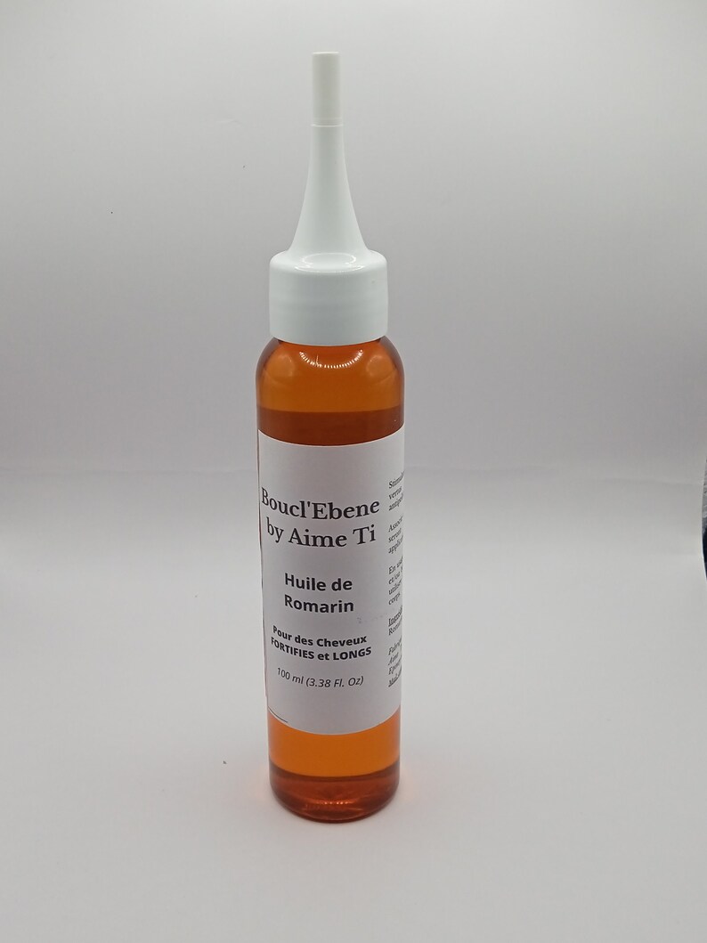 May include: A brown glass bottle with a white dropper top. The bottle is labeled "Boucl'Ebene by Aime Ti Huile de Romarin Pour des Cheveux FORTIFIES et LONGS 100 ml (3.38 FL. Oz)"
