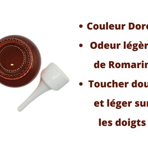 May include: A brown glass bottle with a white dropper top. The bottle contains a liquid that is golden in color. The text on the image reads: "Couleur Dor&eacute;e, Odeur l&eacute;g&egrave;re de Romarin, Toucher doux et l&eacute;ger sur les doigts."