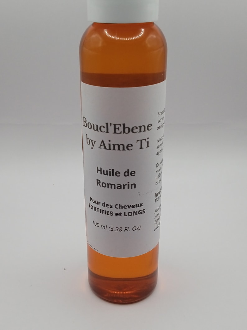 May include: A brown glass bottle with a white label that reads "Boucl'Ebene by Aime Ti" and "Huile de Romarin" for hair that is fortified and long. The bottle contains 100 ml (3.38 fl oz) of product.