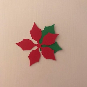 May include: A red paper poinsettia with green paper leaves. The poinsettia is a traditional Christmas decoration.