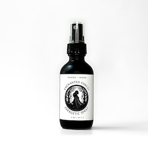 May include: A black glass spray bottle with a white label featuring the text "ENCHANTED FOREST ENERGETIC SPRAY". The label also includes a silhouette of a person in a forest. The bottle contains 2 oz (56.7 g) of product.