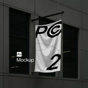 May include: A white rectangular vertical banner hanging from a black metal bracket on a dark gray building facade. The banner features large black letters 'PC' and the number '2' with thin black intersecting lines across the fabric surface.