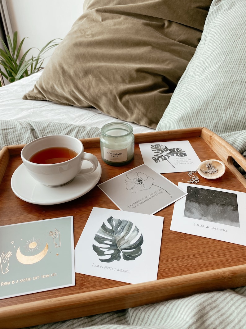 May include: A wooden tray with a white teacup, a candle, and five cards with inspirational quotes. The quotes are: "Today is a sacred gift from life", "I am in perfect balance", "I am worthy of all that I desire, only within each moment I live", "I trust my inner voice", and "I am worthy of all that I desire, only within each moment I live".