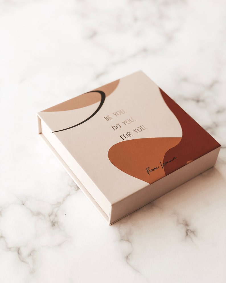 May include: A white box with a brown and beige abstract design. The box has the text "Be you. Do you. For you." and "From Lovemore" printed on it.