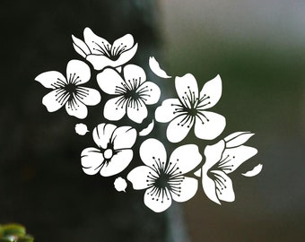 May include: A close-up of a white flower blossom with five petals, surrounded by green leaves, growing on a tree branch. The background is blurred and out of focus.