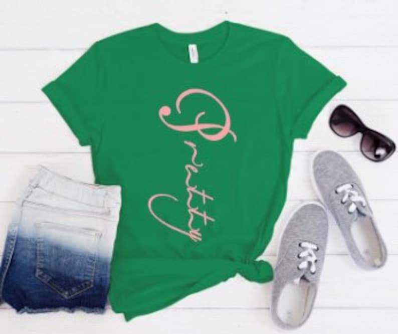 May include: Green t-shirt with a pink cursive word "Pretty" on the front.