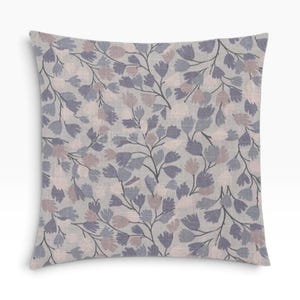 May include: A square throw pillow featuring a light gray background with a repeating pattern of stylized flowers and leaves in shades of muted purple, dusty pink, and dark gray. The fabric has a visible woven texture throughout the surface.