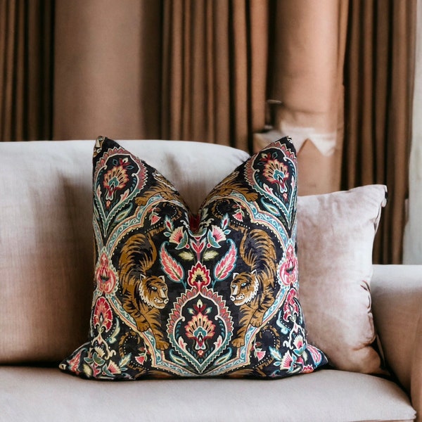 Könnte beinhalten: Ein dekoratives Kissen mit schwarzem Hintergrund und einem farbenfrohen Paisley-Muster mit Tigern. Das Kissen liegt auf einem hellbeigen Sofa.