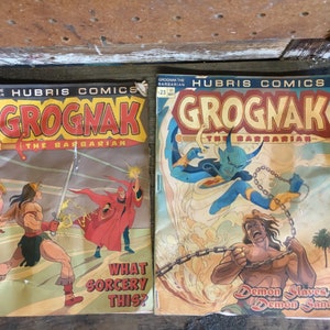 May include: Two vintage comic book covers featuring the character Grognac the Barbarian. The first cover shows Grognac fighting a sorcerer with a red robe. The second cover shows Grognac fighting a blue demon with horns. Both covers feature the text "Hubris Comics" and "Grognak the Barbarian".
