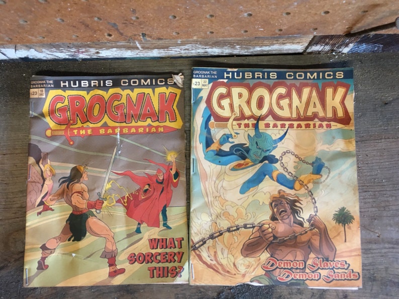 May include: Two vintage comic book covers featuring the character Grognac the Barbarian. The first cover shows Grognac fighting a sorcerer with a red robe. The second cover shows Grognac fighting a blue demon with horns. Both covers feature the text "Hubris Comics" and "Grognak the Barbarian".