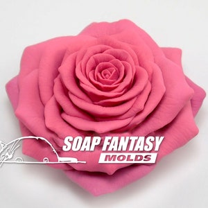 May include: A large, pink rose flower mold for soap making. The mold is made of silicone and has a detailed design. The mold is made by Soap Fantasy Molds.