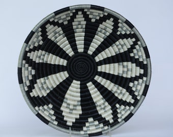Peut inclure: Un panier rond tissé avec un motif géométrique saisissant. Le design présente des bandes alternées de noir, de blanc et de gris, rayonnant d'une spirale centrale. Ce panier décoratif est idéal pour la décoration intérieure.
