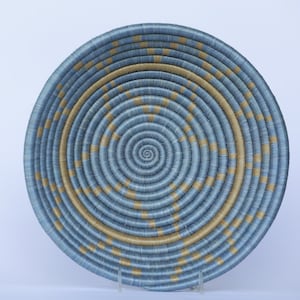 May include: A woven basket with a blue and gold pattern. The basket is round and has a spiral design.