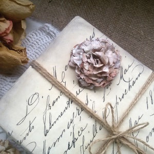 May include: A vintage-style letter tied with twine and decorated with a delicate, light brown and white paper flower. The letter is addressed to "Mr. O' France" and dated "May 1890".
