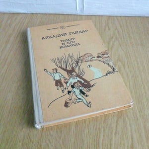May include: A vintage paperback book titled "Arkady Gaidar Timur and his team" with a brown cover and an illustration of three boys in a field.