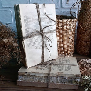 Puede incluir: Una pila de libros antiguos atados con cuerda, sobre una superficie de madera. Los libros están rodeados de cestas tejidas y plantas secas.