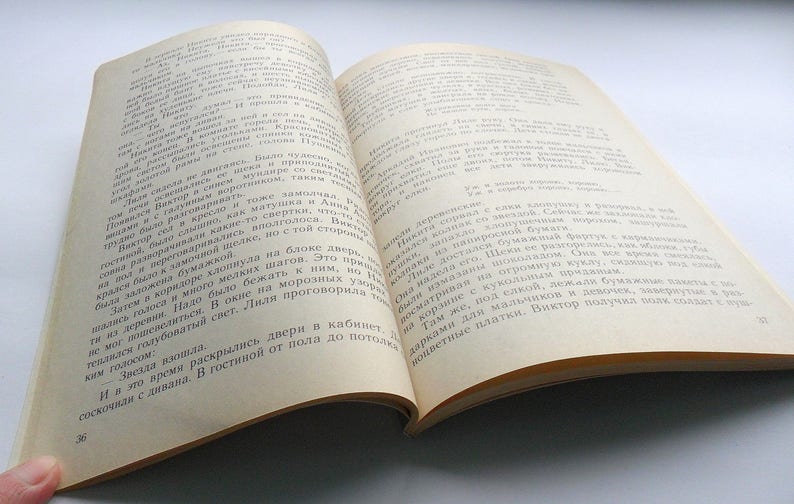 May include: Open book with white pages and black text. The text is in Russian. The book is open to a page with the text "Звезда взошла" and "СОСКОЧИЛИ с дивана. В гостиной от пола до потолка..."