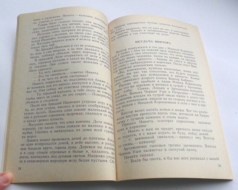 May include: A vintage book with a worn, yellowed cover. The title of the book is "The Misadventures of Victor". The text on the page describes a group of children playing a game of war.