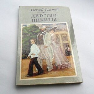 May include: A vintage paperback book cover with a painting of three people walking in a garden. The book title is "Детство Никиты" and the author is "Алексей Толстой".