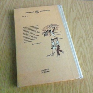 May include: A tan book with a black and white illustration of two children walking. The book's title is "ШКОЛЬНАЯ БИБЛИОТЕКА" and the author is "Лев Кассиль". The book is published by "ДОНЕЦК "ДОНБАС"".