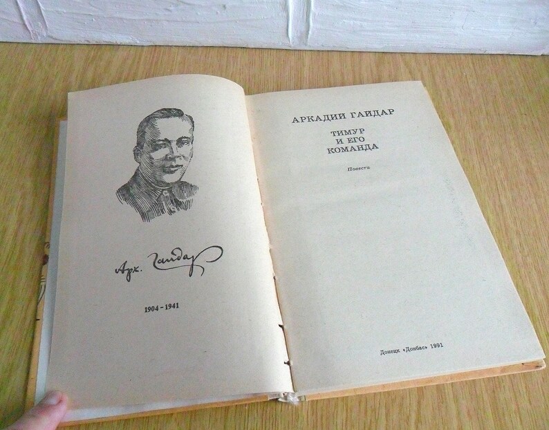 May include: A black and white illustration of a man with a signature and the text "Arkady Gaidar Timur and his team" in Russian. The text "1904-1941" is also visible.