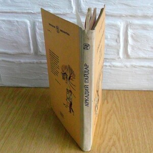 May include: A tan-colored book with the title "Аркадий Гайдар" on the spine. The book is part of a series called "Детская Библиотека".
