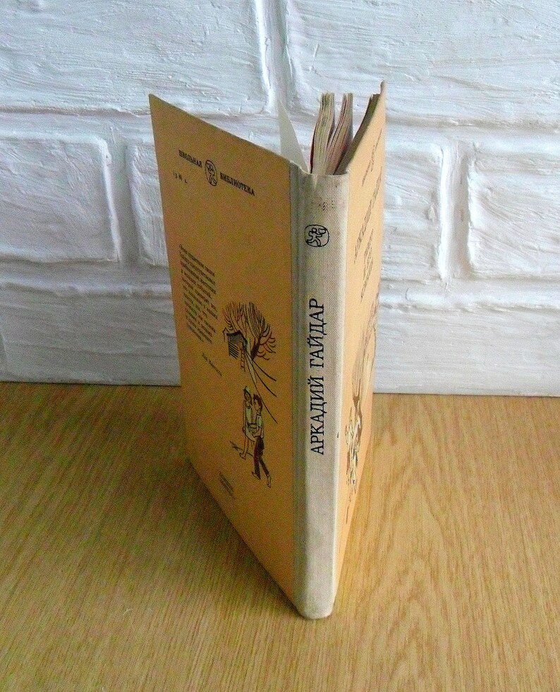 May include: A tan-colored book with the title "Аркадий Гайдар" on the spine. The book is part of a series called "Детская Библиотека".