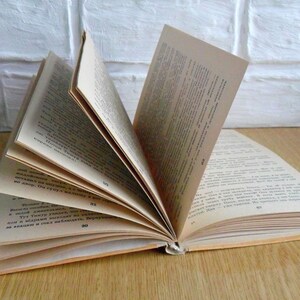 May include: An open book with pages filled with text in a foreign language. The book is lying open on a wooden surface.