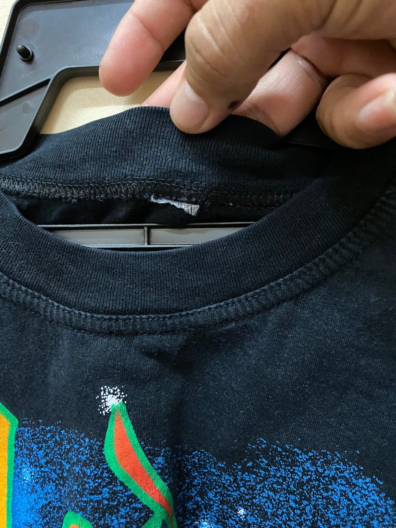 Op de afbeelding: Zwart T-shirt met een kleurrijke grafische print. De print heeft een blauw, groen, rood en geel ontwerp met een witte omtrek. Het shirt heeft een ronde hals en korte mouwen.