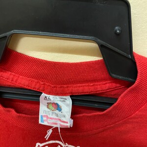 May include: Red Fruit of the Loom t-shirt with a white graphic of a cartoon devil. The tag says "XL Adult 100% Cotton Preshrunk" and "Made in U.S.A."