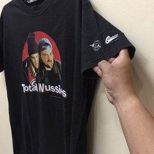 May include: Black t-shirt with a red circle graphic featuring two men with the text "Total Wussies". The t-shirt has a white "Graphiti Design" logo on the sleeve.