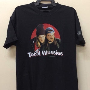 May include: Black t-shirt with a red circle graphic featuring two men with the text "Total Wussies" printed below.
