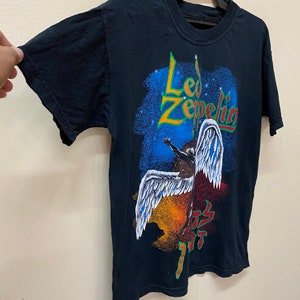 Op de afbeelding: Zwart T-shirt met een kleurrijke grafische print van een gevleugelde figuur en de tekst "Led Zeppelin".