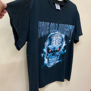 May include: Black t-shirt with a blue and white graphic of a skull with red eyes. The graphic says "Stone Cold University Class of 97" and has a WWF logo.
