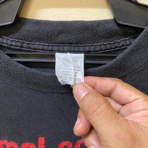May include: Black t-shirt with red text that reads "Animal Scream" and a white graphic image. The tag on the shirt reads "100% Cotton, Care: Machine wash cold, Tumble dry low, Do not bleach, Do not iron, Do not dry clean."