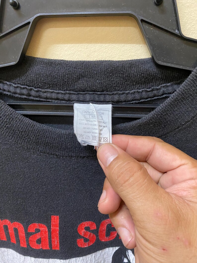 May include: Black t-shirt with red text that reads "Animal Scream" and a white graphic image. The tag on the shirt reads "100% Cotton, Care: Machine wash cold, Tumble dry low, Do not bleach, Do not iron, Do not dry clean."