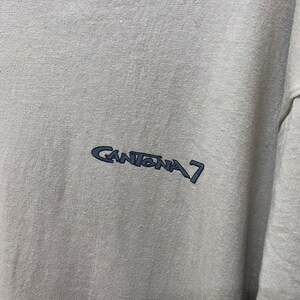 Może przedstawiać: Jasnoszary t-shirt z haftowanym czarnym logo z napisem "Cantona 7".