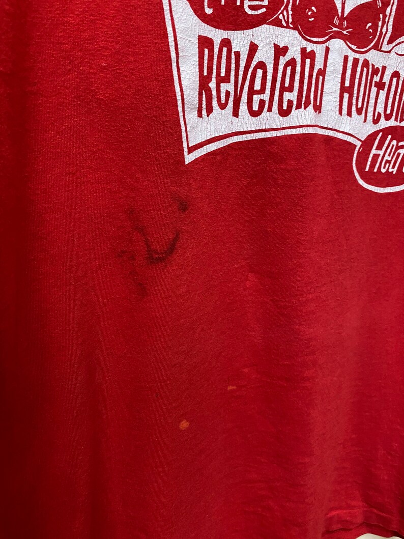 May include: Red t-shirt with a white graphic that says "The Reverend Horton Heat" with a cartoon image of a person wearing a hat and holding a guitar.