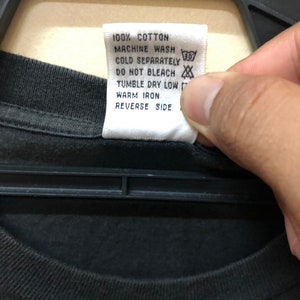 May include: White care label with black text that reads "100% Cotton, Machine Wash Cold Separately, Do Not Bleach, Tumble Dry Low, Warm Iron, Reverse Side". The label has a 30 degree symbol and a symbol that looks like a cross through a circle.