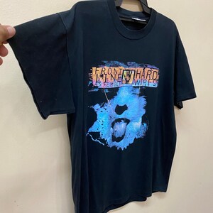 May include: Black t-shirt with a graphic print of a blue and purple mouth with a tongue sticking out. The text "FRONT LINE HARD ASSEMBLY WIRED" is printed on the shirt.