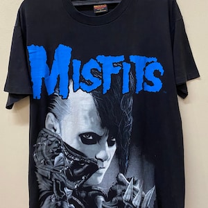 May include: Black t-shirt with a blue "Misfits" graphic and a black and white image of a person with a mohawk.