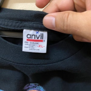 May include: Black t-shirt with a graphic print of a cartoon character. The tag says "Anvil" and "Pre-Shrunk 100% Cotton Made in USA" and "XL".