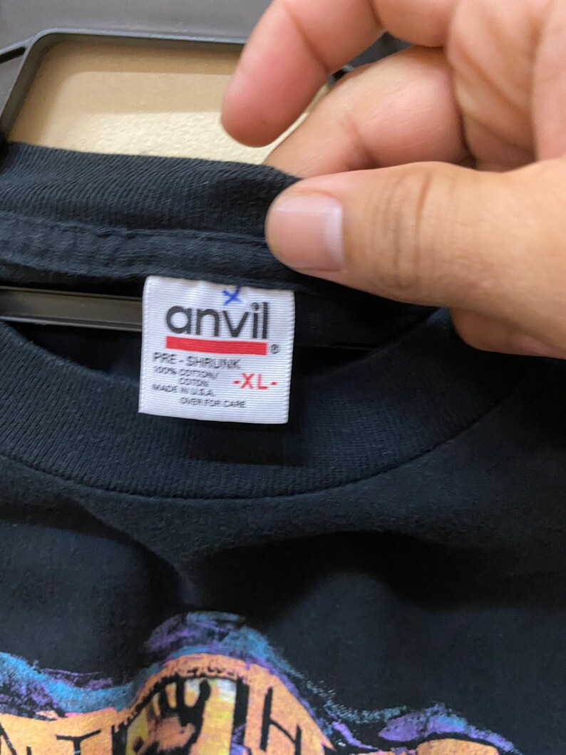 May include: Black t-shirt with a graphic print of a cartoon character. The tag says "Anvil" and "Pre-Shrunk 100% Cotton Made in USA" and "XL".