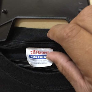 May include: Black Hanes Heavyweight t-shirt tag with white text. The tag reads "Preshrunk 100% Cotton, Assembled in Mexico, Adult L (42-44)/G/G".