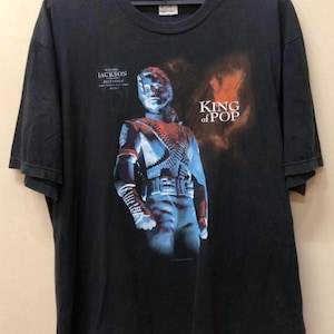 May include: Black t-shirt with a graphic of Michael Jackson from his "HIStory" album. The graphic features a blue and red image of Michael Jackson with the text "King of Pop".