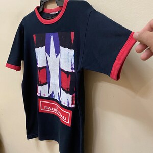 May include: Black t-shirt with a red and blue graphic print of a star and the word "RADIOHEAD" in a red box.