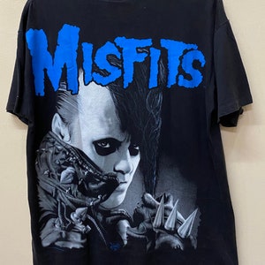 May include: Black t-shirt with a blue "Misfits" graphic and a black and white image of a person with spiky hair and a leather jacket.