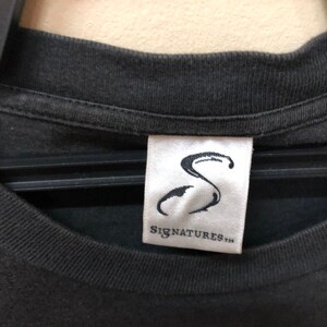 May include: Black t-shirt with a white tag that says "Signatures" and a stylized "S" logo.